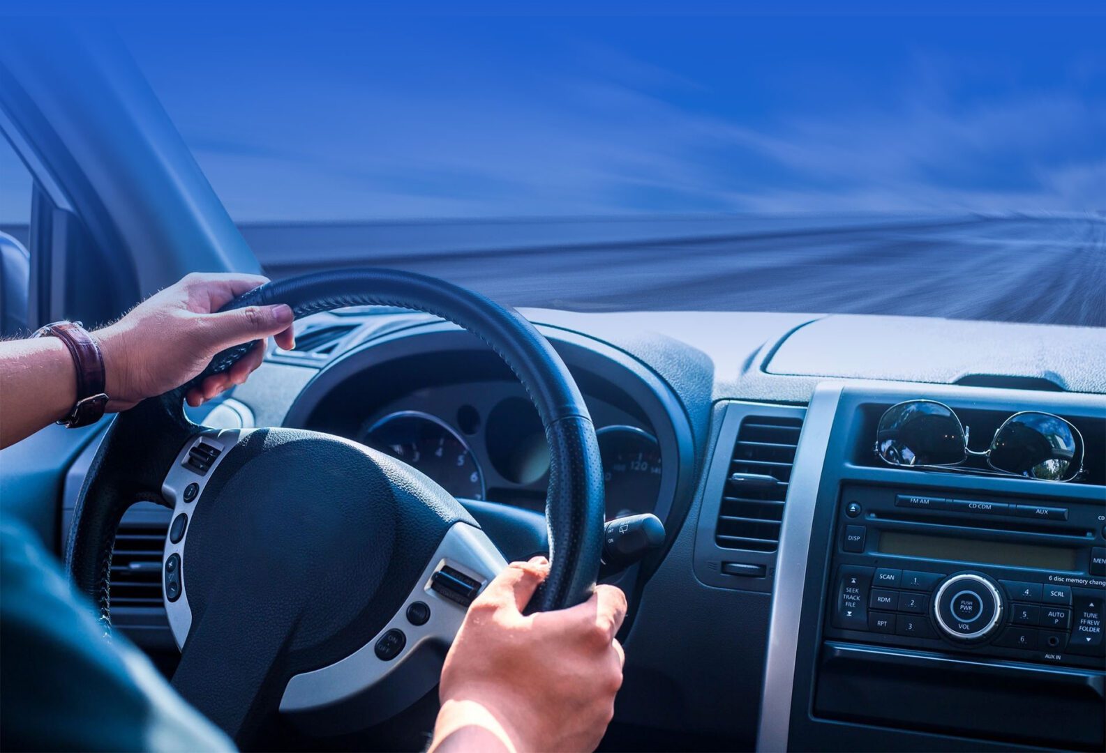 Driver's hands on steering wheel with dashboard view, driving at high speed on a blurred road.