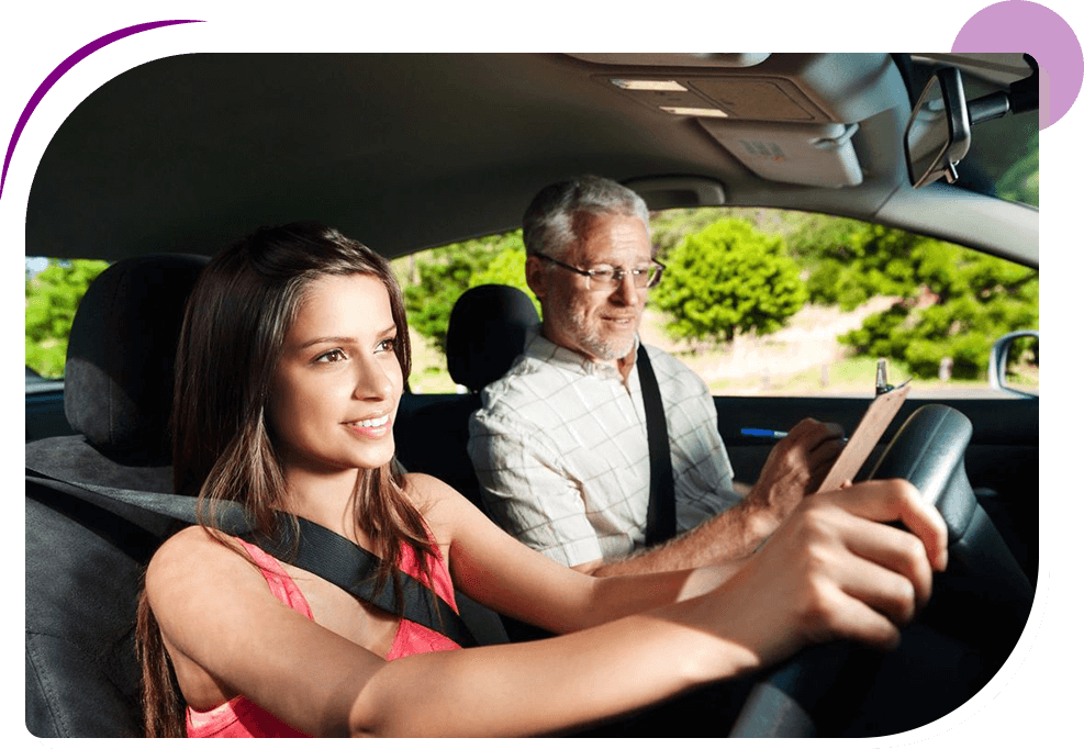 Young woman driving a car, focused on the road, with an older man in the passenger seat, both wearing seat belts, in a daylight setting.